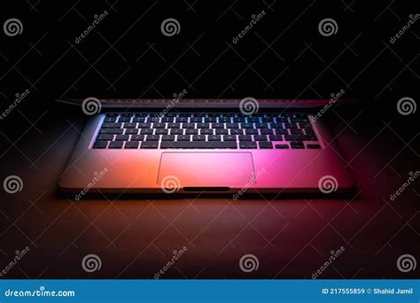 A Laptop Half Closed In The Dark With Colourful Glow Stock Image