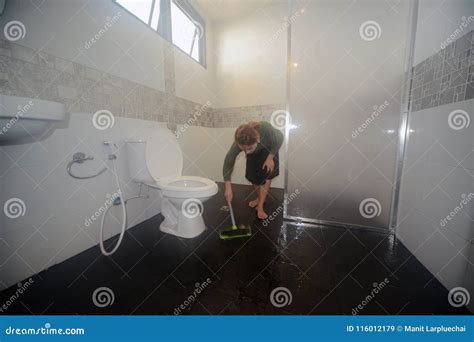 Asian Female Maid Or Housekeeper Cleaning Floor With Swab In Toilet