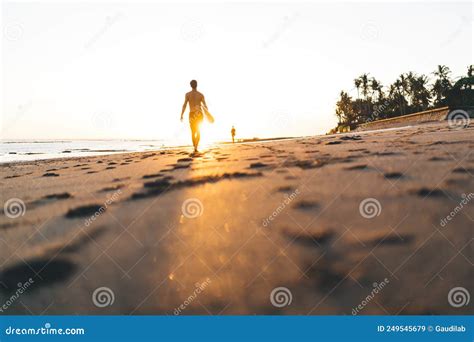 Faceless Athlete Strolling On Beach With Surfboard At Bright Sunset