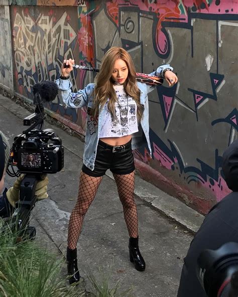 A Woman Standing In Front Of A Graffiti Covered Wall With Her Hands Up