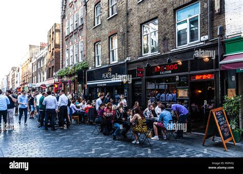 Customers Dining Al Fresco At Row Of Restaurants On Berwick Street Soho London England UK