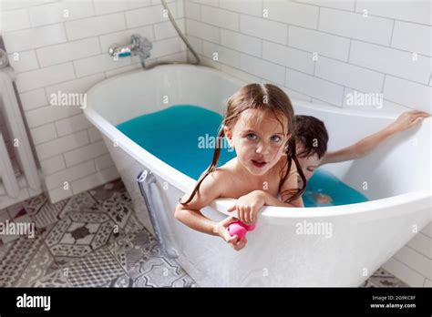 From Above Of Adorable Little Brother And Sister Bathing In Bathtub With Blue Water And Having