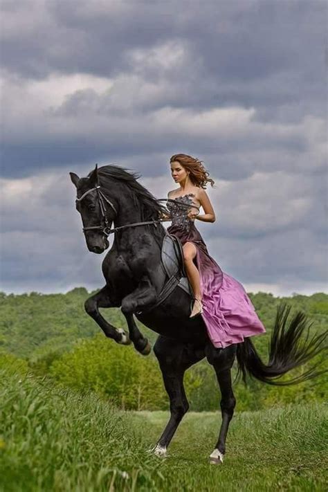 A Woman Riding On The Back Of A Black Horse Through A Lush Green Field