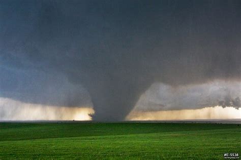 A Large Dark Tornado Looms Over Green Kansas Prairie Near The Town Of
