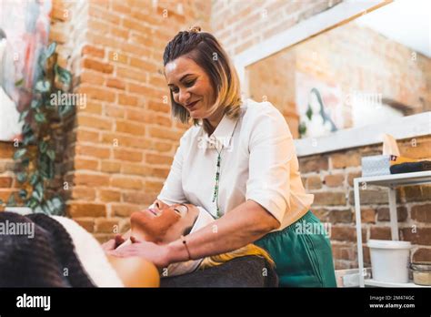 Happy Massage Therapist During Work Smiling Caucasian Woman Doing A Massage To Her Client Who