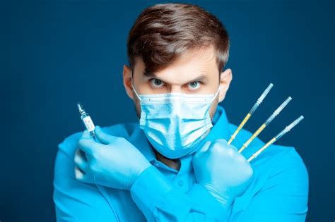 premium photo a doctor in a medical mask and gloves in a blue uniform poses with thin