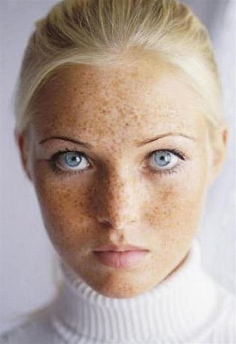 A Woman With Freckled Hair And Blue Eyes Wearing A White Turtle Neck