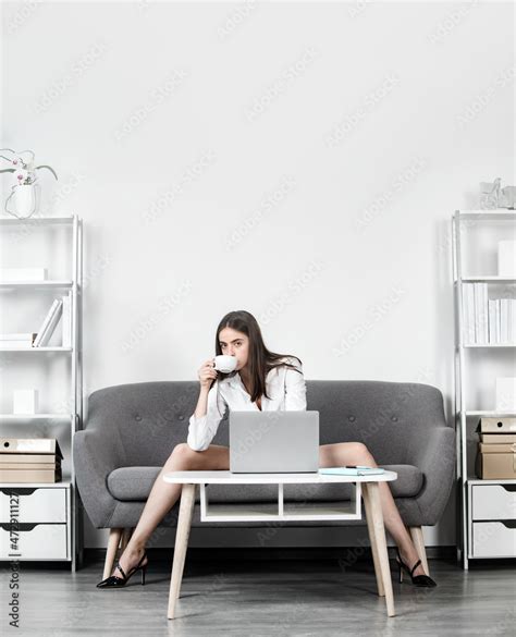seductive secretary with sexy legs drinking coffee sit on sofa in office sexy business woman