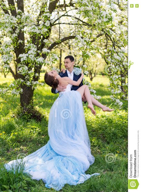 Young Wedding Couple Embracing In Blooming Spring Garden