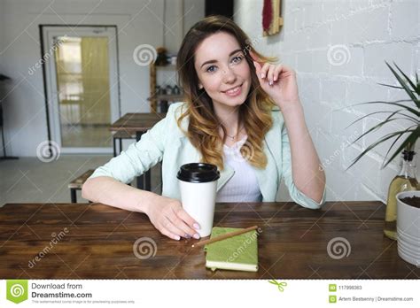 Beautiful Young Girl Sitting At The Table With Coffee And Smiling