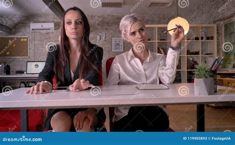 Young Lesbian Woman Touching Knee Of Other Woman Under Desk In Modern Office Lesbian Concept