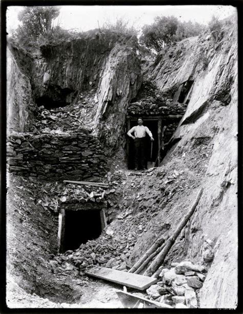 Entrances To Two Mine Shafts Man With Shovel Standing At One Of The