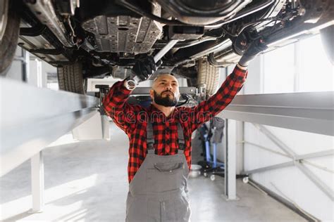 Auto Mechanic Working Underneath A Lifted Car Auto Mechanic Working In