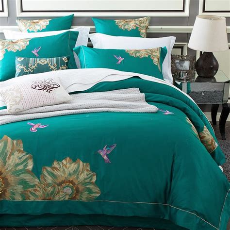 A Bed With Green Comforter And Pillows On It