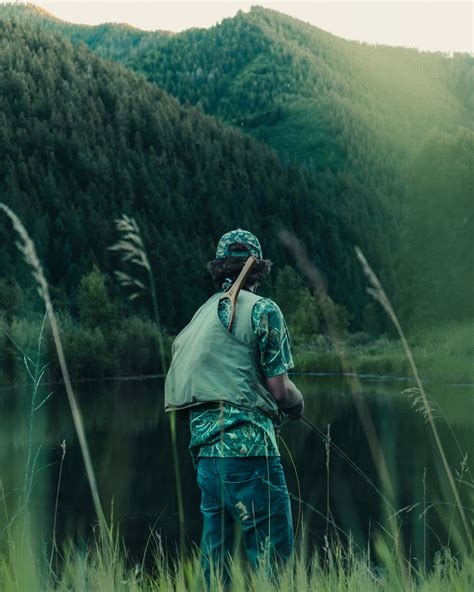 A Man With A Fishing Net On His Back Over A Mountain Lake Fisherman