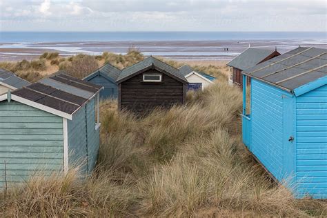 Several Beach Huts In Sand Dunes Looking Towards The Sea By Stocksy