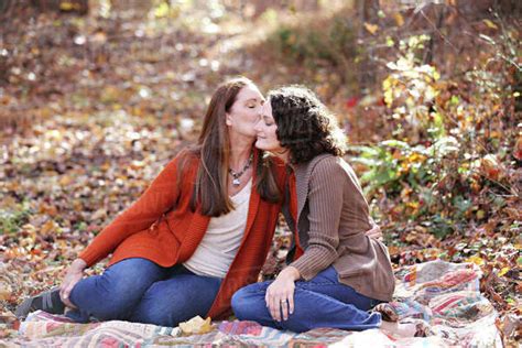 Caucasian Lesbian Kissing Cheek Of Girlfriend In Autumn Leaves Stock Photo Dissolve