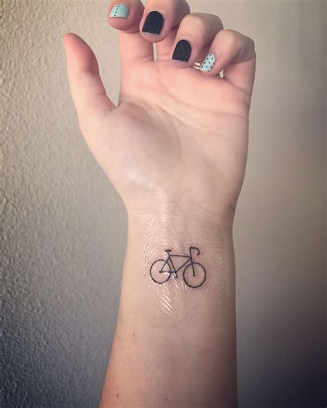 A Womans Hand With A Small Bicycle Tattoo On It
