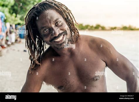 cheerful shirtless african american male looking at camera on blurred background in jamaica