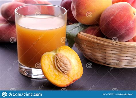 Peach Juice In A Glass Next To A Fresh Peach Closeup On A Dark