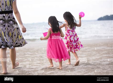 Asian Chinese Mum And Daughters Playing Sand Together At Beach Outdoor