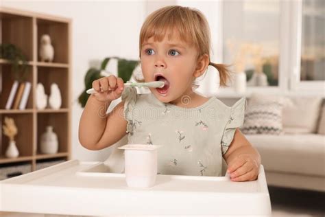 Cute Little Child Eating Tasty Yogurt With Spoon At Home Stock Photo