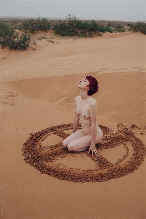Naked Redhead Girl Drawing Sign On Sand With Her Hands By Stocksy