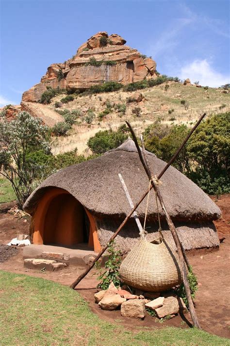 There Is A Hut Made Out Of Sticks And Grass In Front Of A Rock Formation