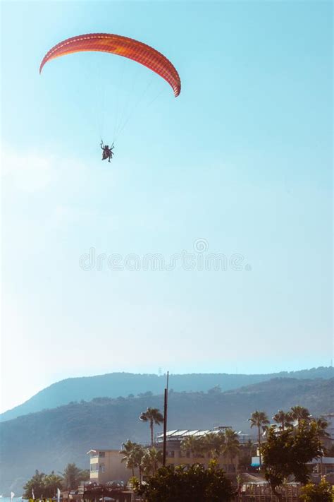 Skydiver With A Red Parachute Buildings And Mountain In The Background