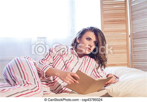Woman In Pajamas Lying On The Bed And Reading A Book Holiday CanStock