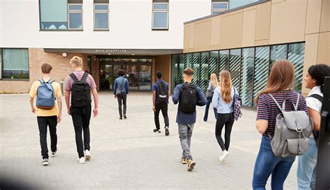 Rear View Of High School Students Walking Into College Building