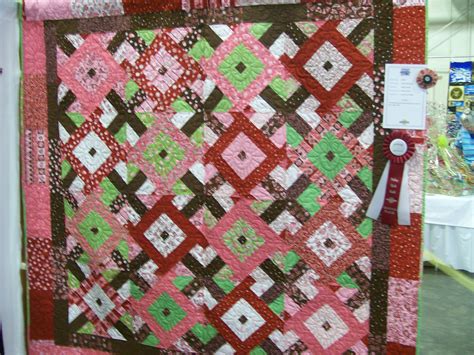 A Pink And Brown Quilt On Display In A Room With Other Items For Sale