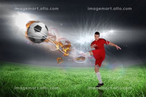 Football Player In Red Kicking Against Football Pitch Under Bright