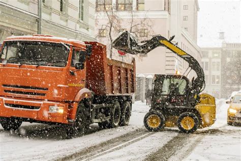 Excavator Load Snow In Truck Clearing Streets Of Snow B Stock Photo