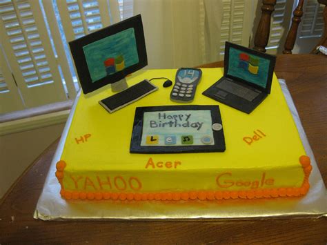 A Birthday Cake That Is On Top Of A Table With Two Laptops And A Cell Phone