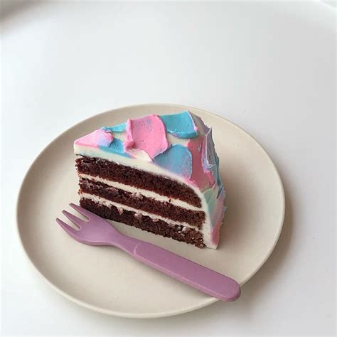 A Piece Of Cake On A Plate With A Pink Fork Next To It And A White