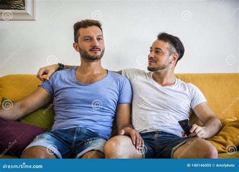 Due Omosessuali Sul Sofà Che Abbracciano A Casa Immagine Stock