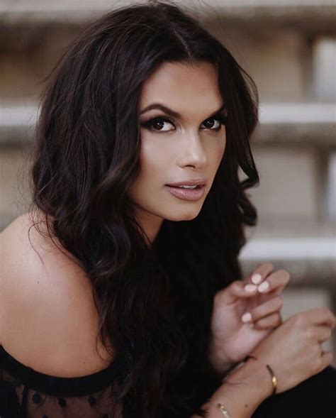 A Woman With Long Dark Hair Wearing A Black Dress And Holding Her Hand