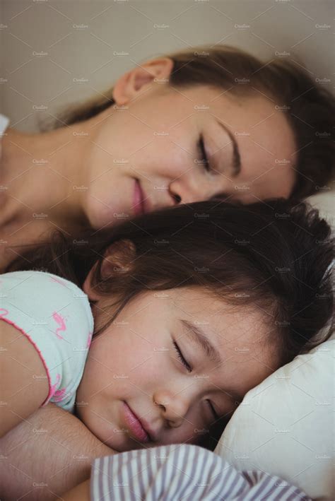 Mother And Daughter Sleeping Together In Bedroom High Quality Stock