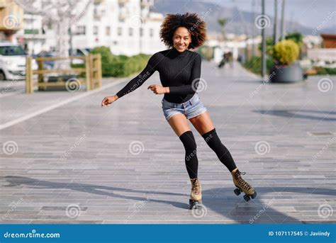 Black Woman On Roller Skates Riding Outdoors On Urban Street Stock