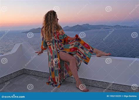 Beautiful Woman In Colorful Dress On Balcony Terrace Looking At Sea And Sunset Resort Stock