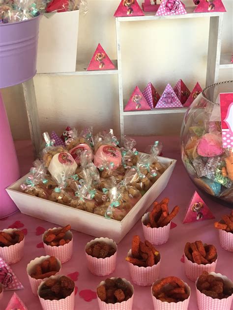 A Pink Table Topped With Lots Of Desserts And Candy Bar Bags Filled