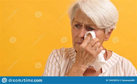 Portrait Of Sad Vulnerable Old Woman Wiping Her Tears Isolated On The