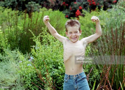Outdoor Portrait Of A Skinny Young Boy Flexing His Muscles High Res