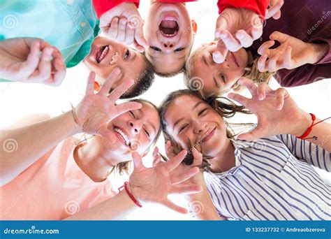 Group Of Children Of Various Ages Standing In Circle Looking Down Into