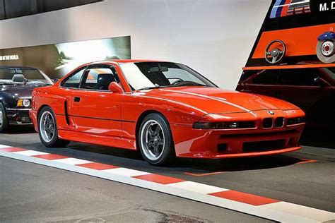 An Orange Car Is Parked Next To Other Cars In A Showroom With Red And