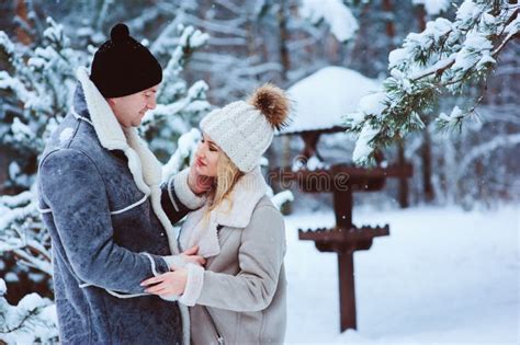 Winter Portrait Of Happy Romantic Couple Embracing And Looking To Each Other Outdoor In Snowy