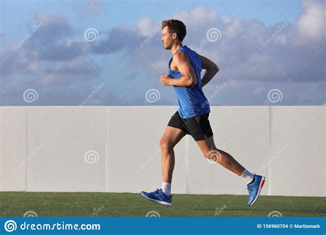 Young Man Runner Running In City Park On Summer Grass Outdoors At