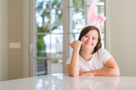 Down Syndrome Woman At Home Wearing Easter Rabbit Ears Pointing And