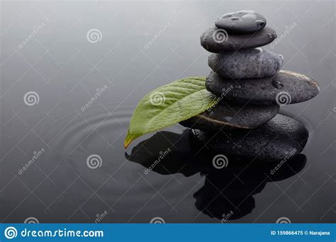 Zen Stones In Balanced Pile And Green Leaf With Water Drops In Water